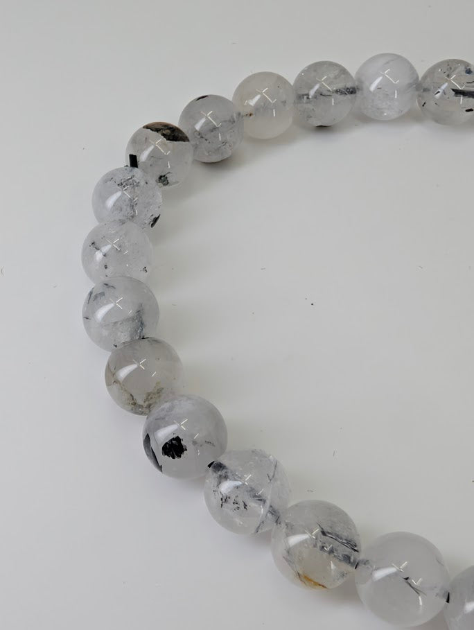 Angled view of polished Herkimer style quartz bracelet showing light refraction