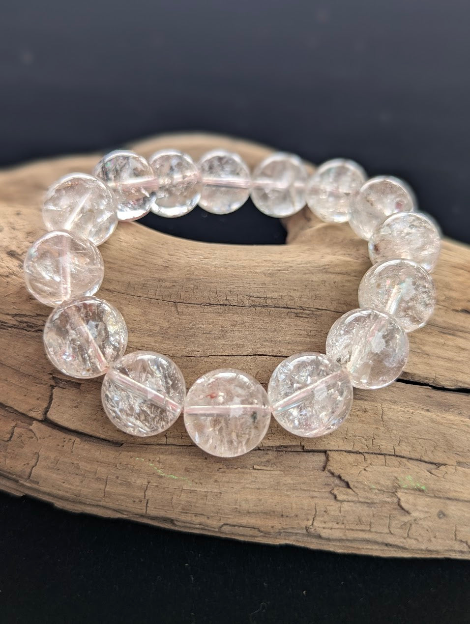 Intuitively selected 14mm statement AAA Grade Himalayan Garden Quartz beaded stretch bracelet displayed on driftwood, showcasing water-clear high-altitude quartz.