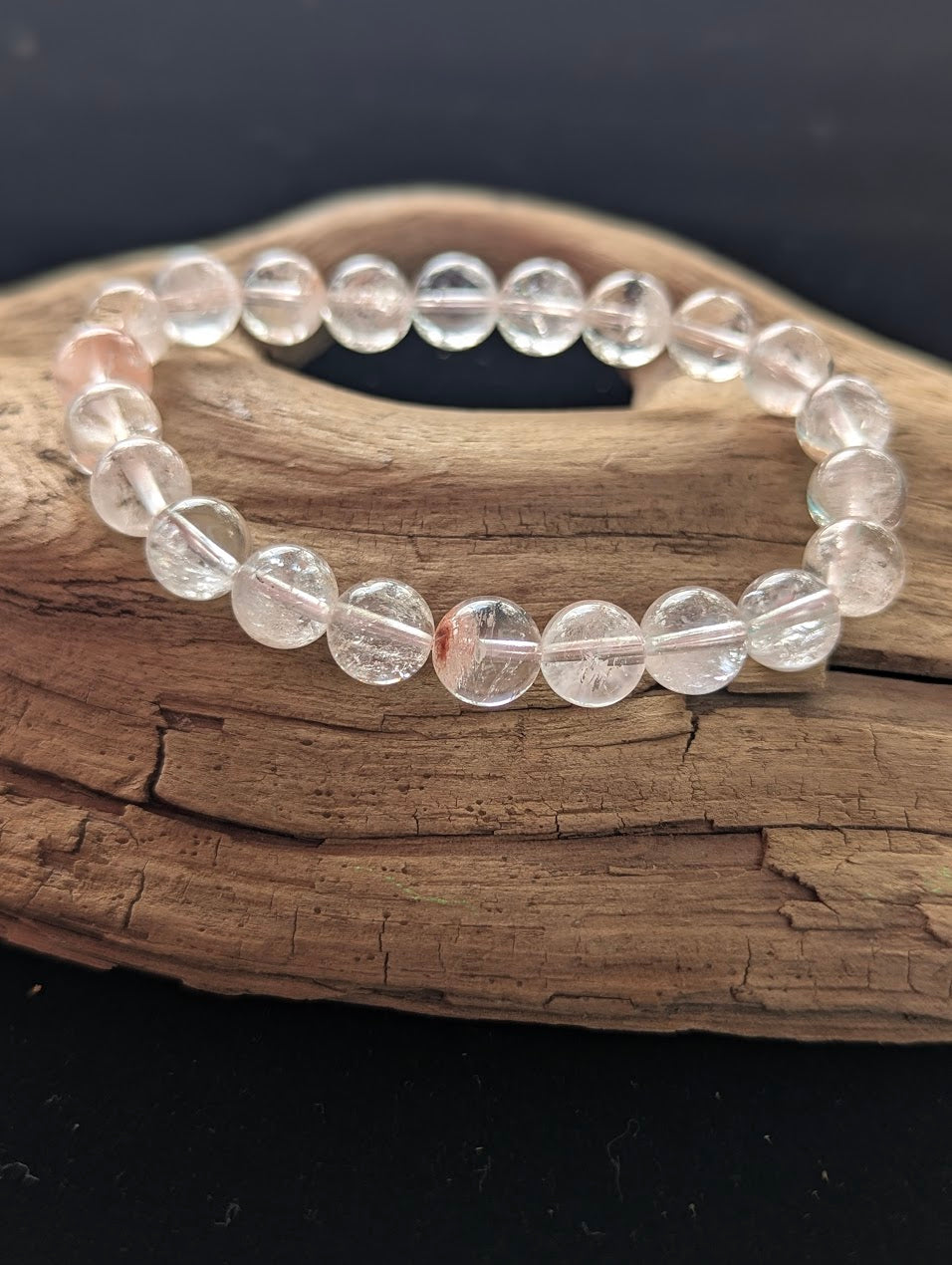 Intuitively selected 9mm AAA Grade Himalayan Garden Quartz beaded stretch bracelet on a driftwood display, showing ice-clear quartz with natural scenic mineral inclusions.