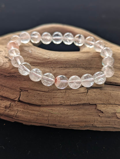 Intuitively selected 9mm AAA Grade Himalayan Garden Quartz beaded stretch bracelet on a driftwood display, showing ice-clear quartz with natural scenic mineral inclusions.