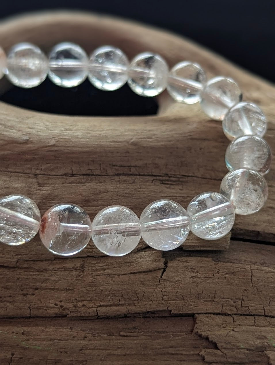 Macro photograph of 9mm Himalayan Garden Quartz beads highlighting the high vitreous lustre and distinct internal lodolite formations.