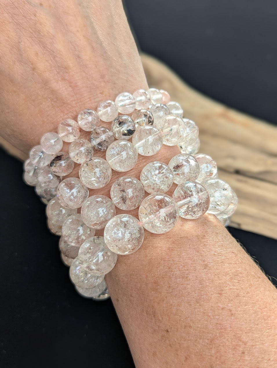Stack of intuitively selected AAA Grade Himalayan Garden Quartz beaded bracelets worn together on a wrist, demonstrating ice-like clarity and natural mineral inclusions.