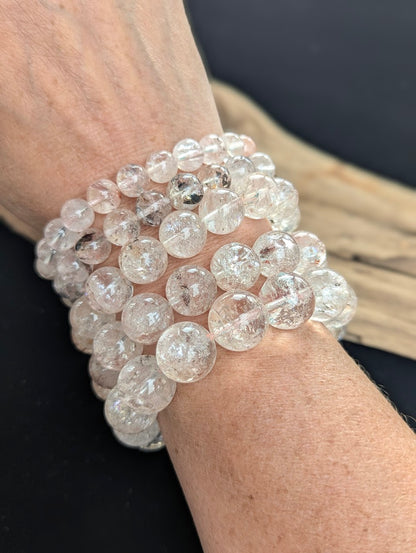 Stack of intuitively selected AAA Grade Himalayan Garden Quartz beaded bracelets worn together on a wrist, demonstrating ice-like clarity and natural mineral inclusions.