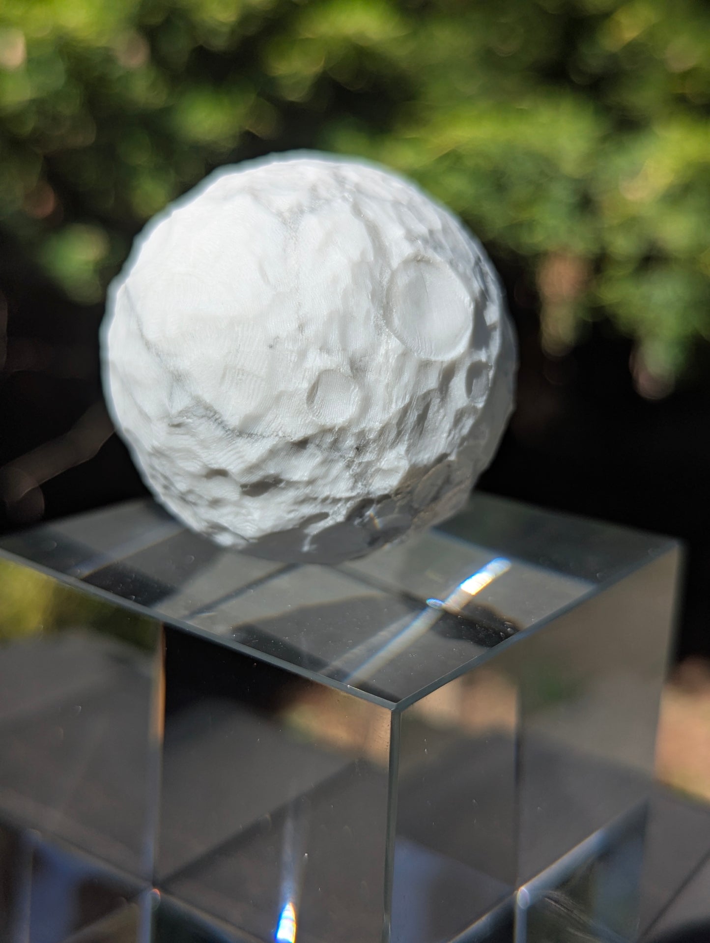 A 50 mm (1.97 in) natural Howlite carved moon sphere showing a porous white structure with grey-to-black matrix webbing.
