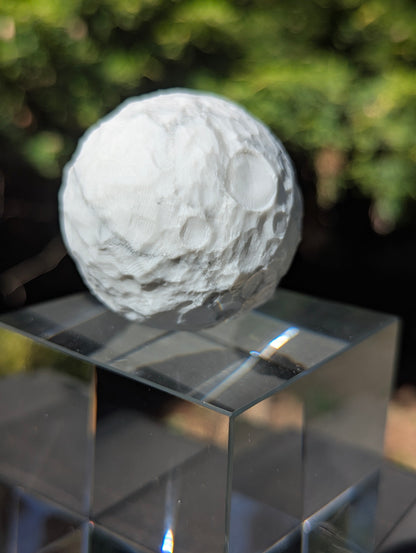 A 50 mm (1.97 in) natural Howlite carved moon sphere showing a porous white structure with grey-to-black matrix webbing.
