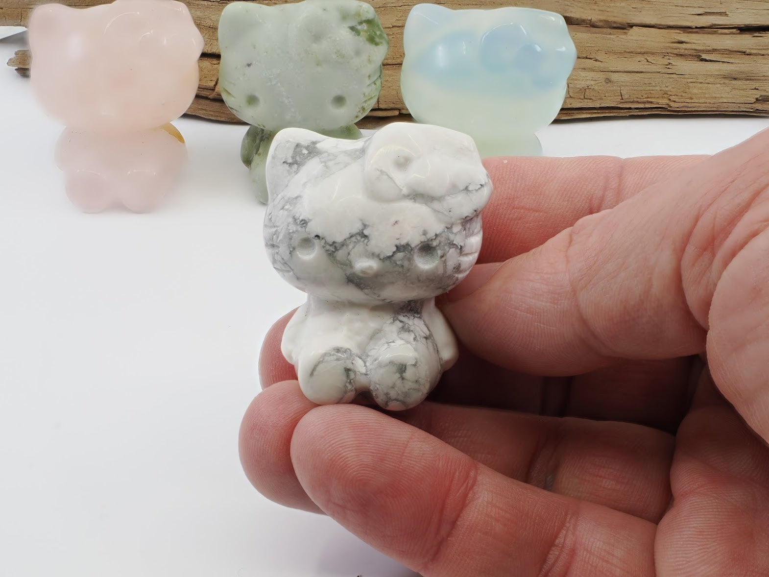 Handheld view of a 40mm Howlite Hello Kitty carving providing a size and scale reference for collectors.