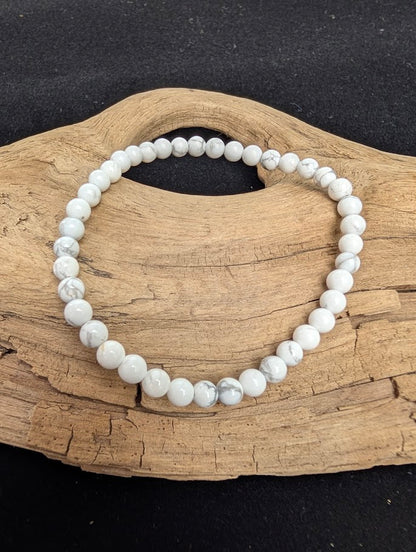 4mm smooth Howlite beaded stretch bracelet resting on a driftwood display, showing a porcelain-white base with dark grey veining.