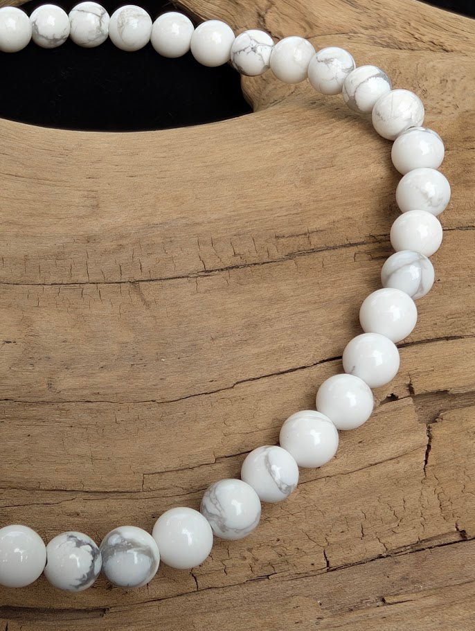 Macro close-up of 4mm smooth Howlite beads highlighting the high-gloss polish and natural grey matrix webbing.