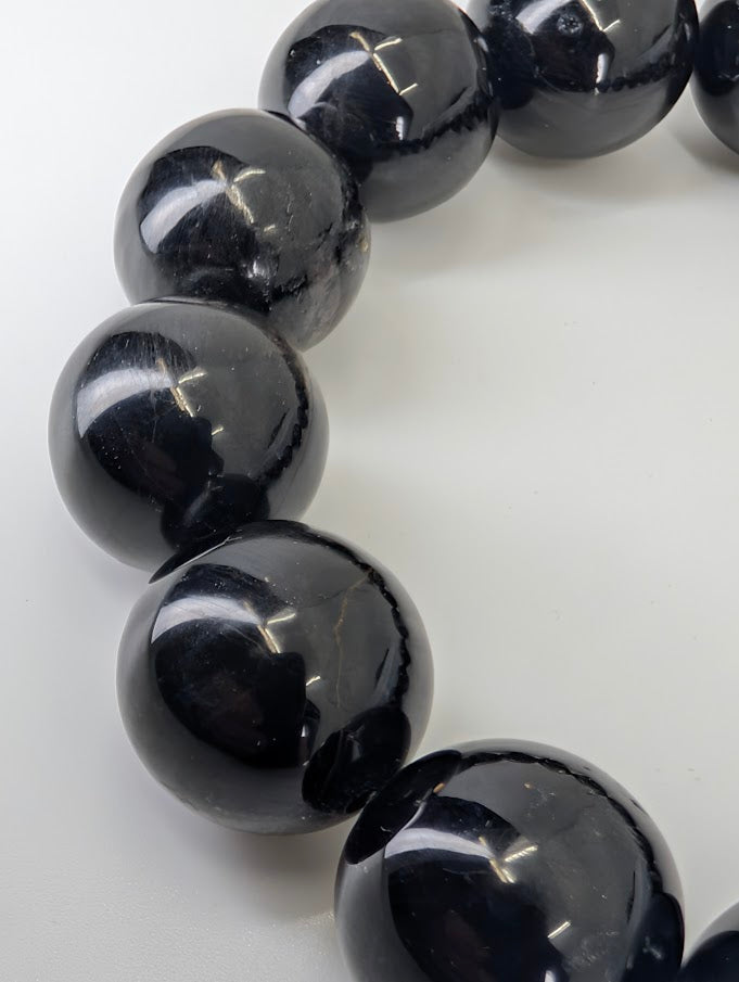 Macro close-up of Hypersthene beads showing internal lamellar reflections and high gloss