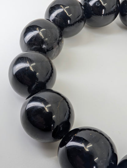 Macro close-up of Hypersthene beads showing internal lamellar reflections and high gloss