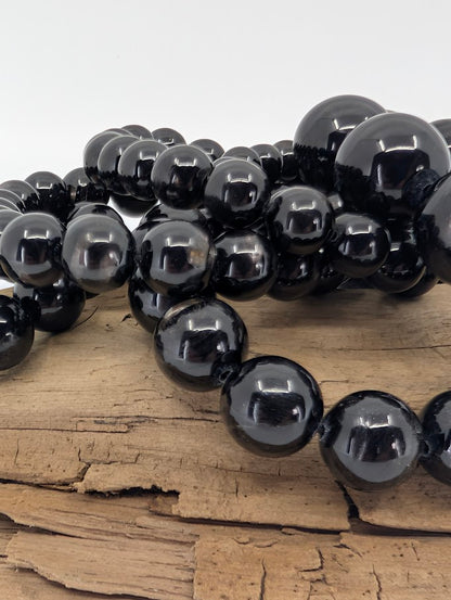 Close-up of Hypersthene beads on wood highlighting glossy polish and silver internal reflections