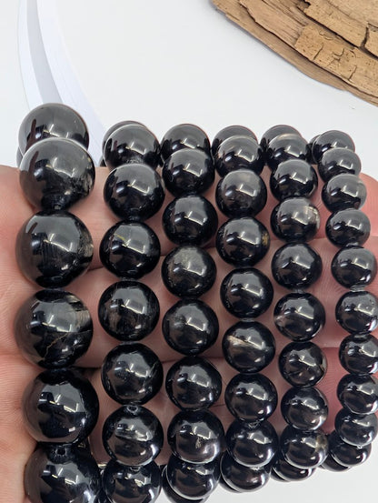 Handheld view of Hypersthene bracelets at an angle emphasizing metallic flash and polish