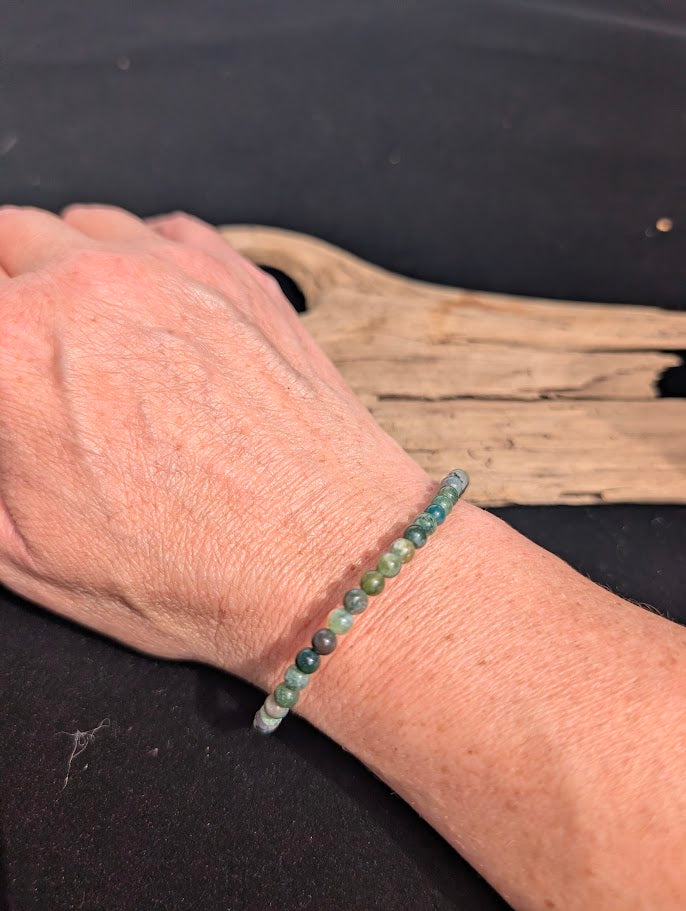 Natural sunlight on a 4mm multi-coloured earthy Indian Agate stretch bracelet worn on a wrist.