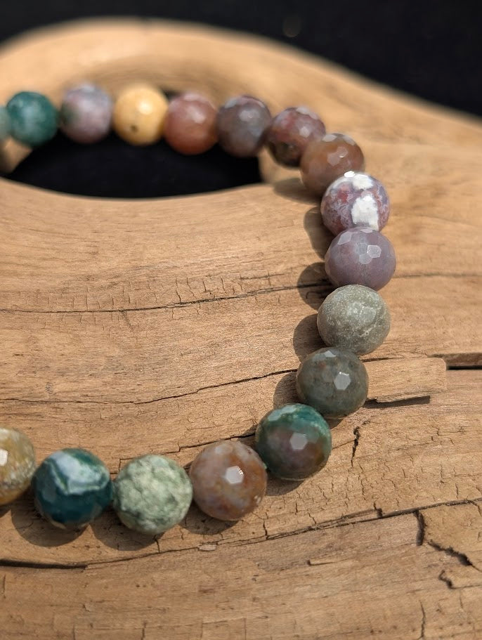Macro view of faceted 8mm Indian Agate beads on driftwood, displaying crisp lapidary cuts and natural chalcedony colour zoning.