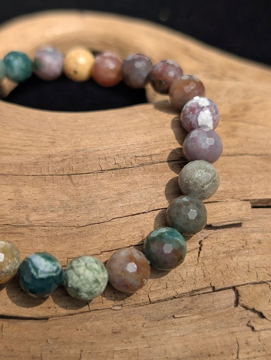 Macro view of faceted 8mm Indian Agate beads on driftwood, displaying crisp lapidary cuts and natural chalcedony colour zoning.
