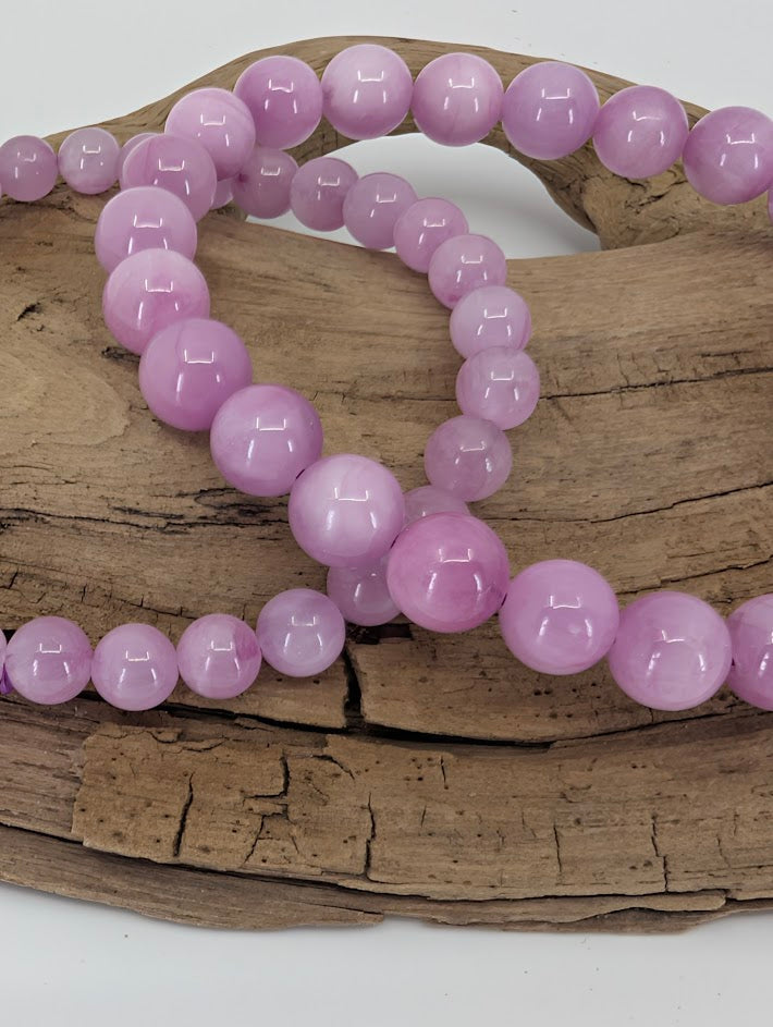Close-up of polished Kunzite beads with luminous lavender-pink sheen