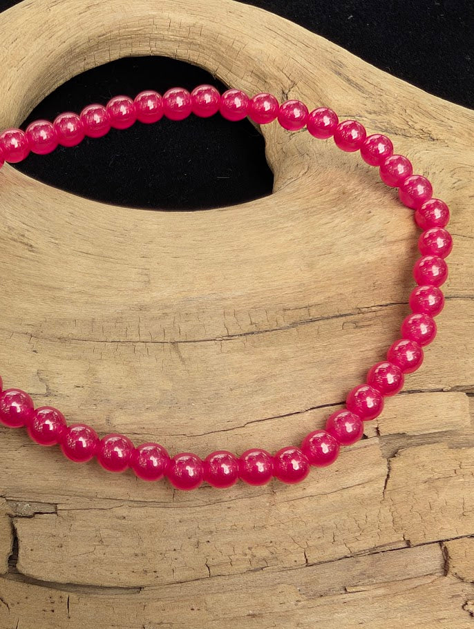 Macro close-up of 4mm polished lab-grown Ruby beads highlighting the high-gloss finish and translucent red tones.