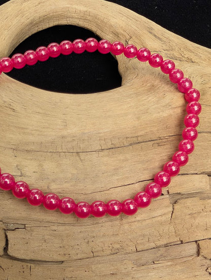 Macro close-up of 4mm polished lab-grown Ruby beads highlighting the high-gloss finish and translucent red tones.