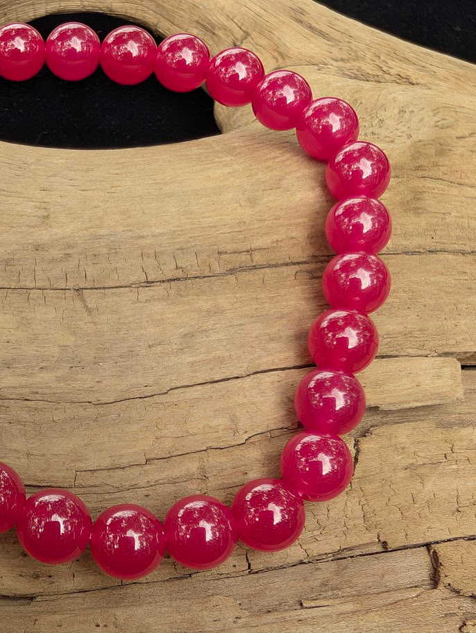 Macro close-up of 6mm polished lab-grown Ruby beads showing high colour saturation and surface reflections.