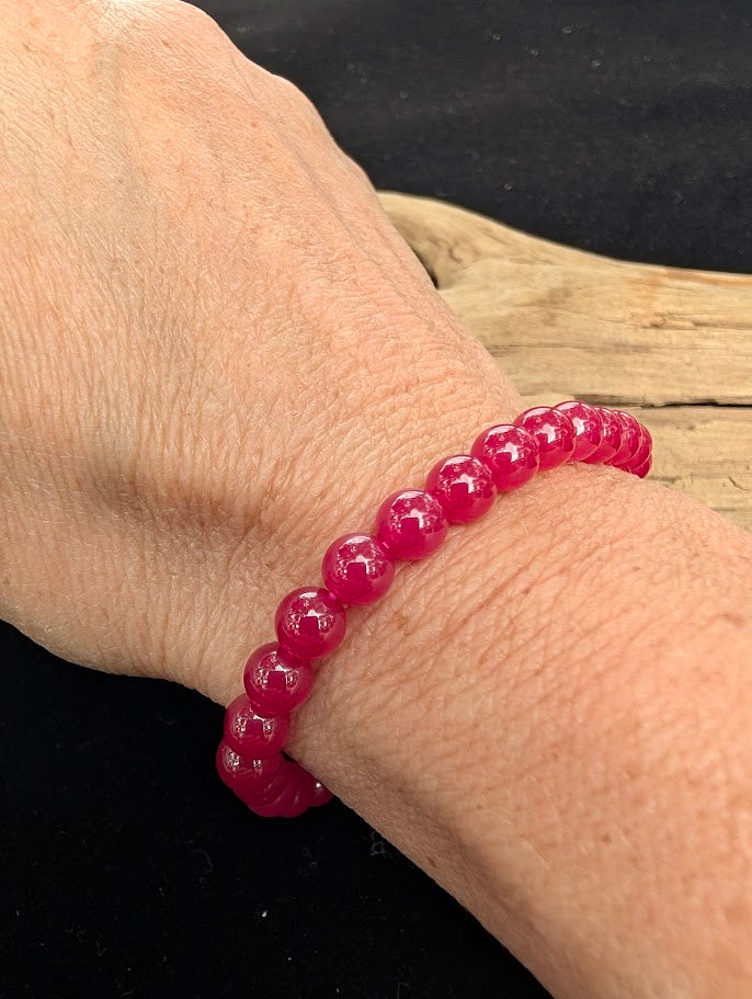 6mm polished lab-grown Ruby beaded stretch bracelet worn on a wrist for delicate size scale.