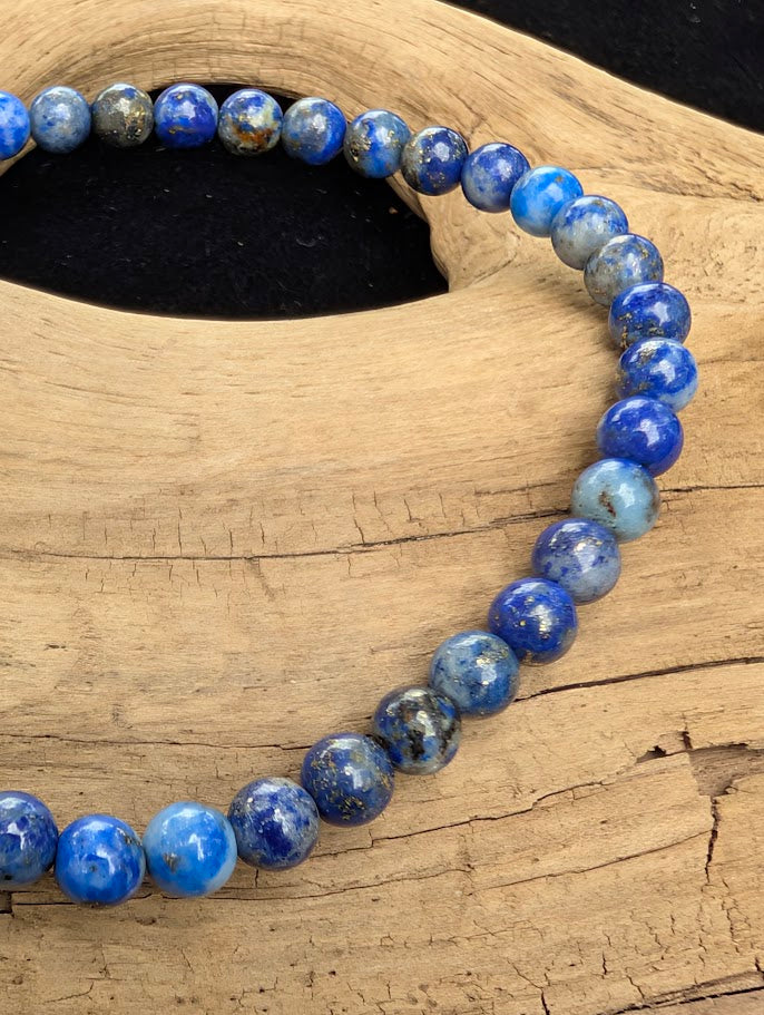 Macro close-up of 4mm polished Lapis Lazuli beads highlighting the high-gloss finish, deep blue lazurite, and golden pyrite flecks.