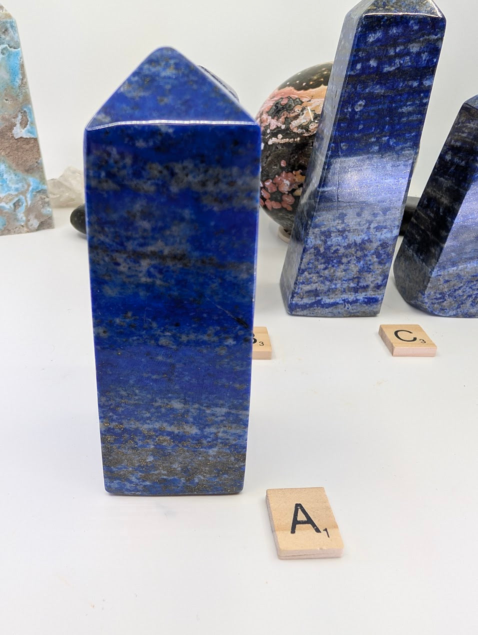 Polished A-Grade Lapis Lazuli tower (obelisk) from Afghanistan, standing 12cm tall, featuring deep royal blue lazurite with distinct white calcite matrix and labeled with Scrabble tile A.