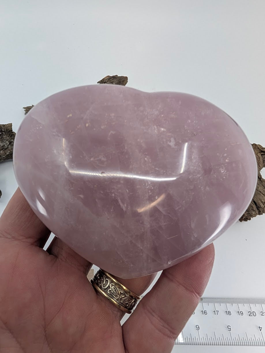 Hand holding Specimen A, a 470g large Rose Quartz heart, showing wide shape.