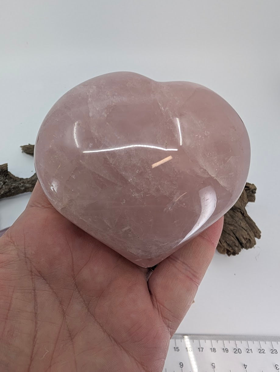 Hand holding Specimen B, a massive 560g Rose Quartz heart, showing thickness and scale.