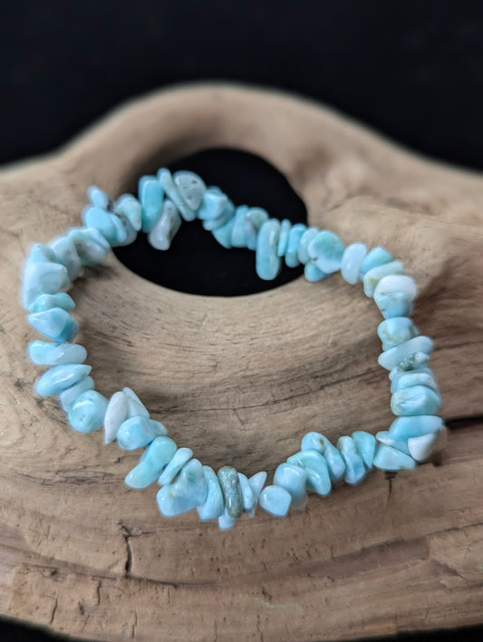 AA Grade natural Larimar chip bracelet from the Dominican Republic resting on natural driftwood, showcasing bright oceanic blue and white patterning.