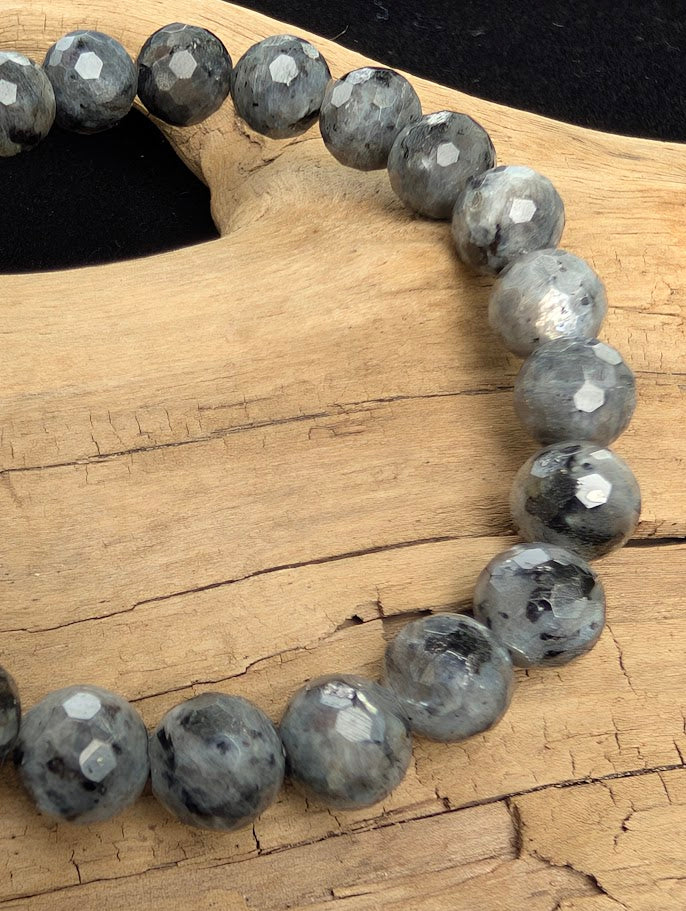 Macro close-up of 8mm faceted Larvikite beads highlighting geometric surface cuts and the natural silver-blue schiller effect.
