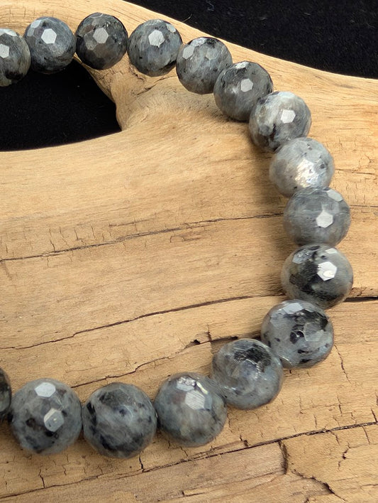 Macro close-up of 8mm faceted Larvikite beads highlighting geometric surface cuts and the natural silver-blue schiller effect.