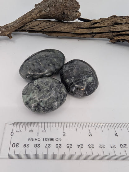 Larvikite palm stones photographed with ruler for size reference