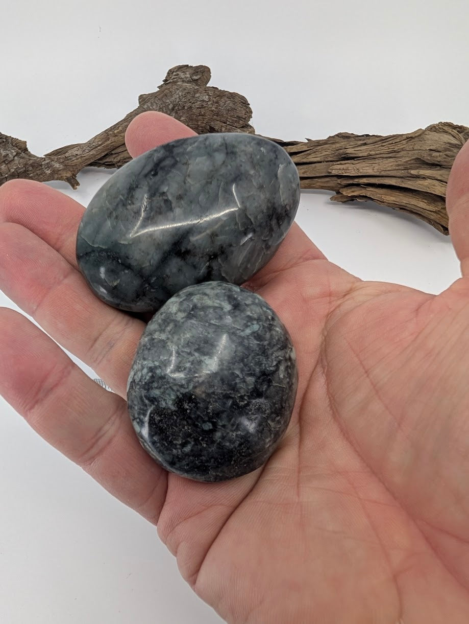 Polished larvikite palm stones held in hand showing size and colour