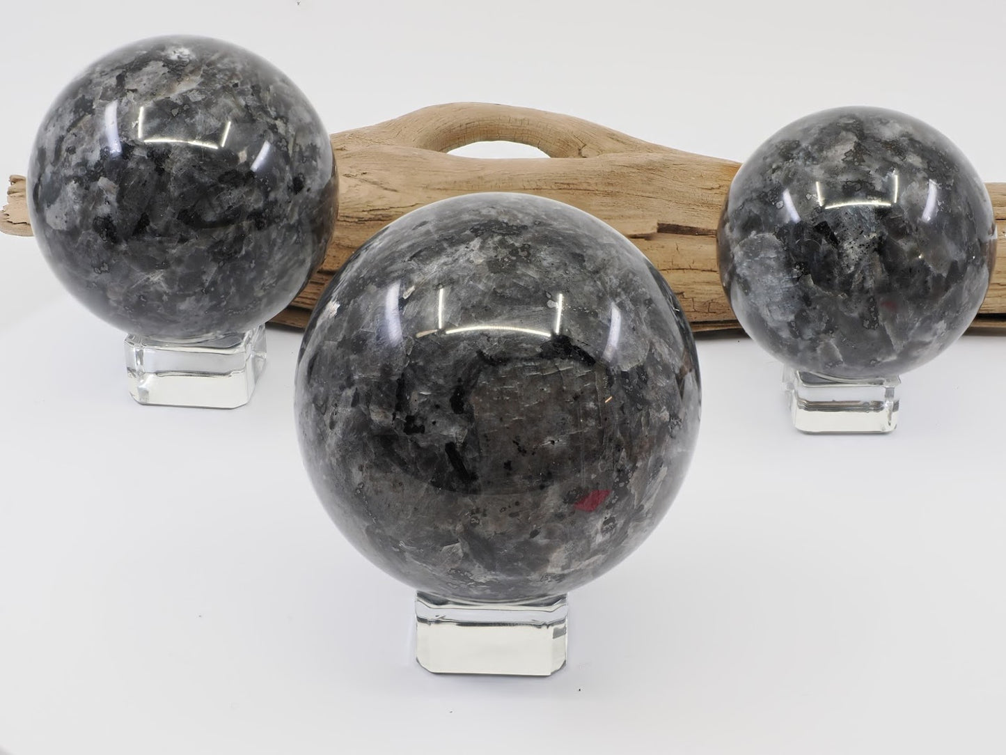 Three polished Larvikite spheres displaying silver flash on crystal stands.