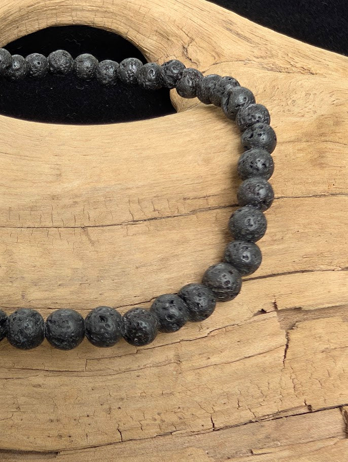 Macro close-up of 4mm Lava Stone beads highlighting the matte finish and natural vesicular pitting.