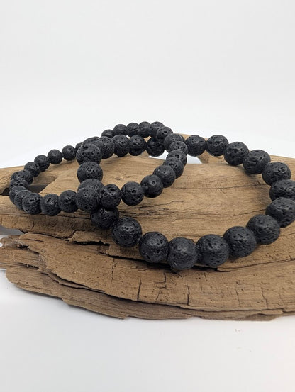 6MM and 8mm matte black lava stone stretch bracelet on driftwood, front view