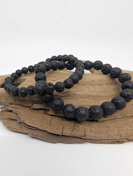 6MM and 8mm matte black lava stone stretch bracelet on driftwood, front view