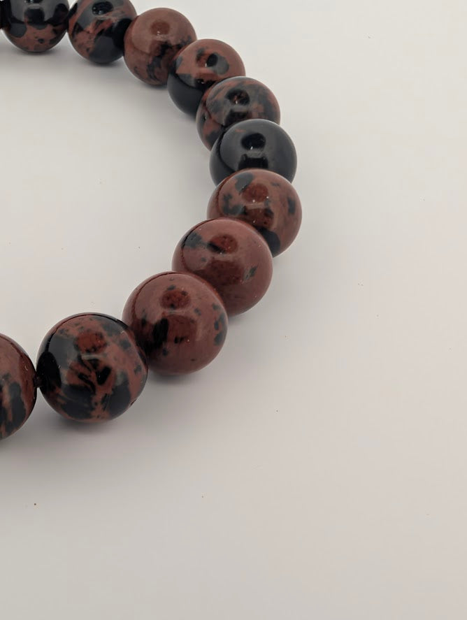 Detailed side view of polished red obsidian beads on elastic cord