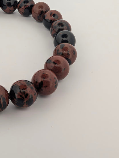 Detailed side view of polished red obsidian beads on elastic cord