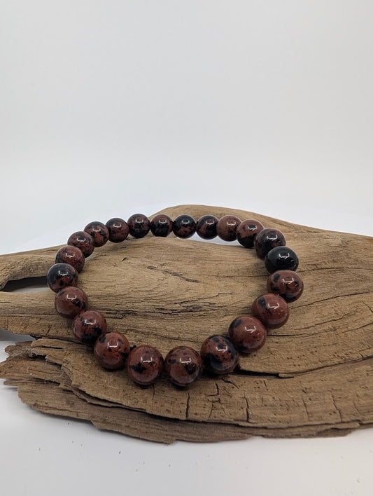 8mm red obsidian bracelet with glossy mahogany and black swirls on driftwood