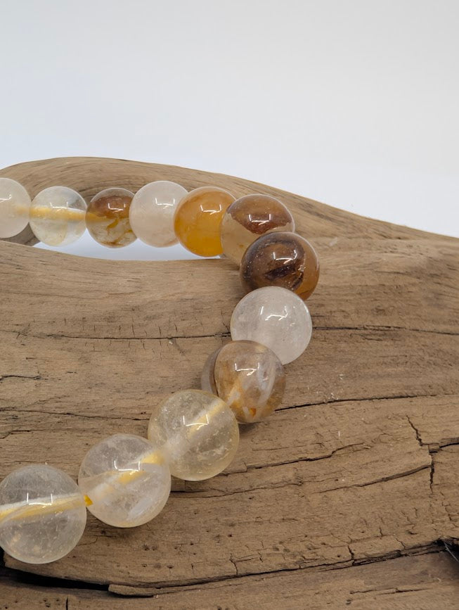 Macro of 8mm Golden Healer Quartz beads showing golden iron-oxide veils
