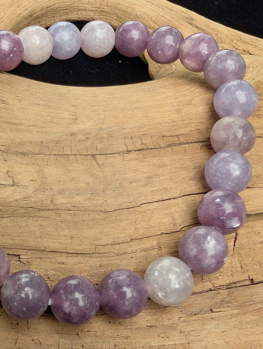 Macro close-up of 8mm polished Lepidolite beads highlighting the high-gloss finish and reflective micaceous structure.