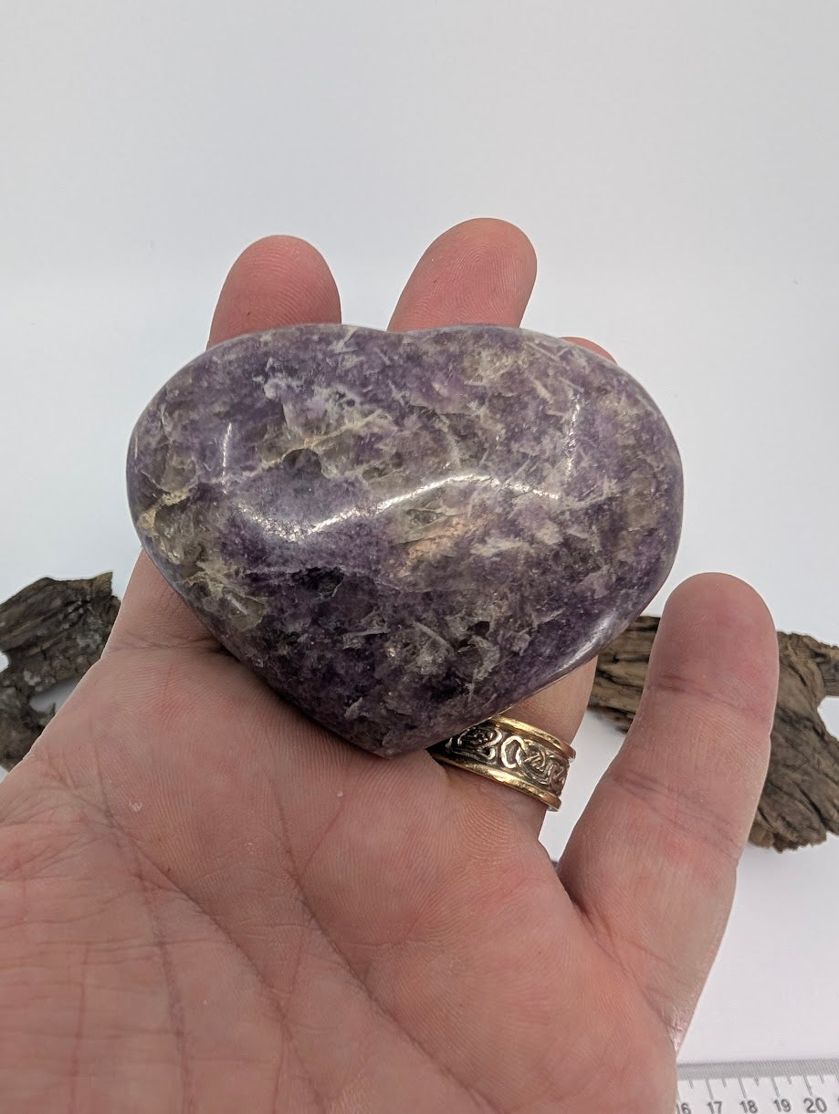 Hand holding a medium 160g Lepidolite heart showing mica texture.