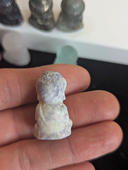 The rear view of a Lepidolite meditating monk totem highlighting the natural purple and white mottled texture of the polished stone.
