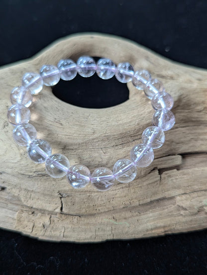Substantial 10mm AA Grade Light Amethyst gemstone bracelet resting on rustic wood, highlighting luminous pastel purple hues.