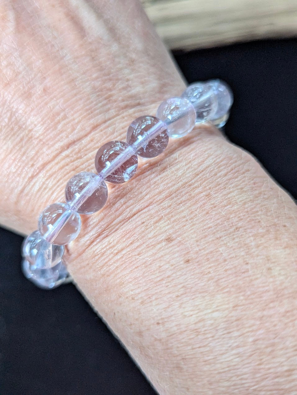 Prominent 10mm Light Amethyst gemstone bracelet styled on a wrist, demonstrating size and glowing clarity.