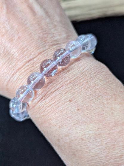 Prominent 10mm Light Amethyst gemstone bracelet styled on a wrist, demonstrating size and glowing clarity.