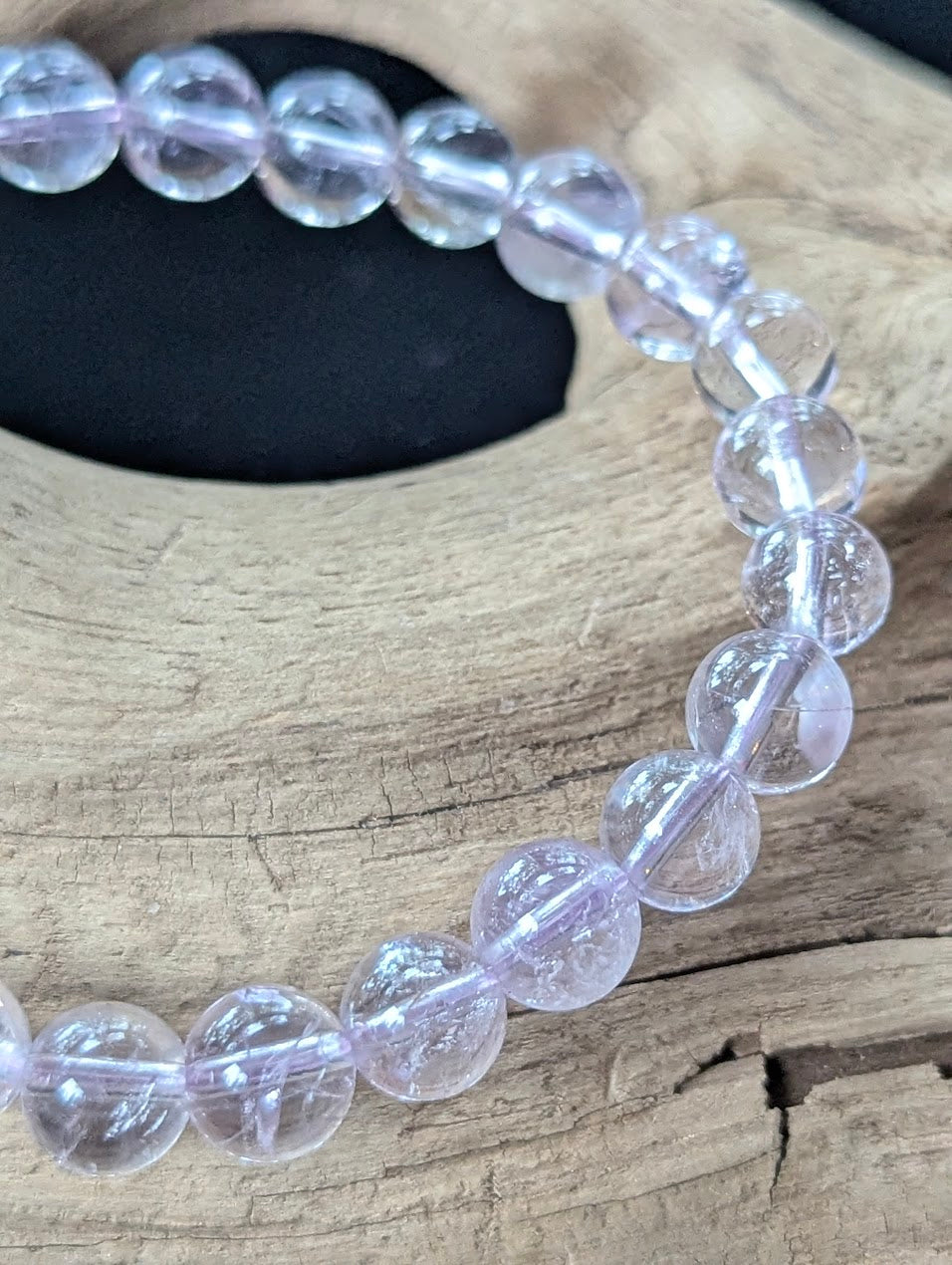 Close-up macro view of 7mm Bolivian Light Amethyst beads highlighting their water-clear translucency and glassy polish.