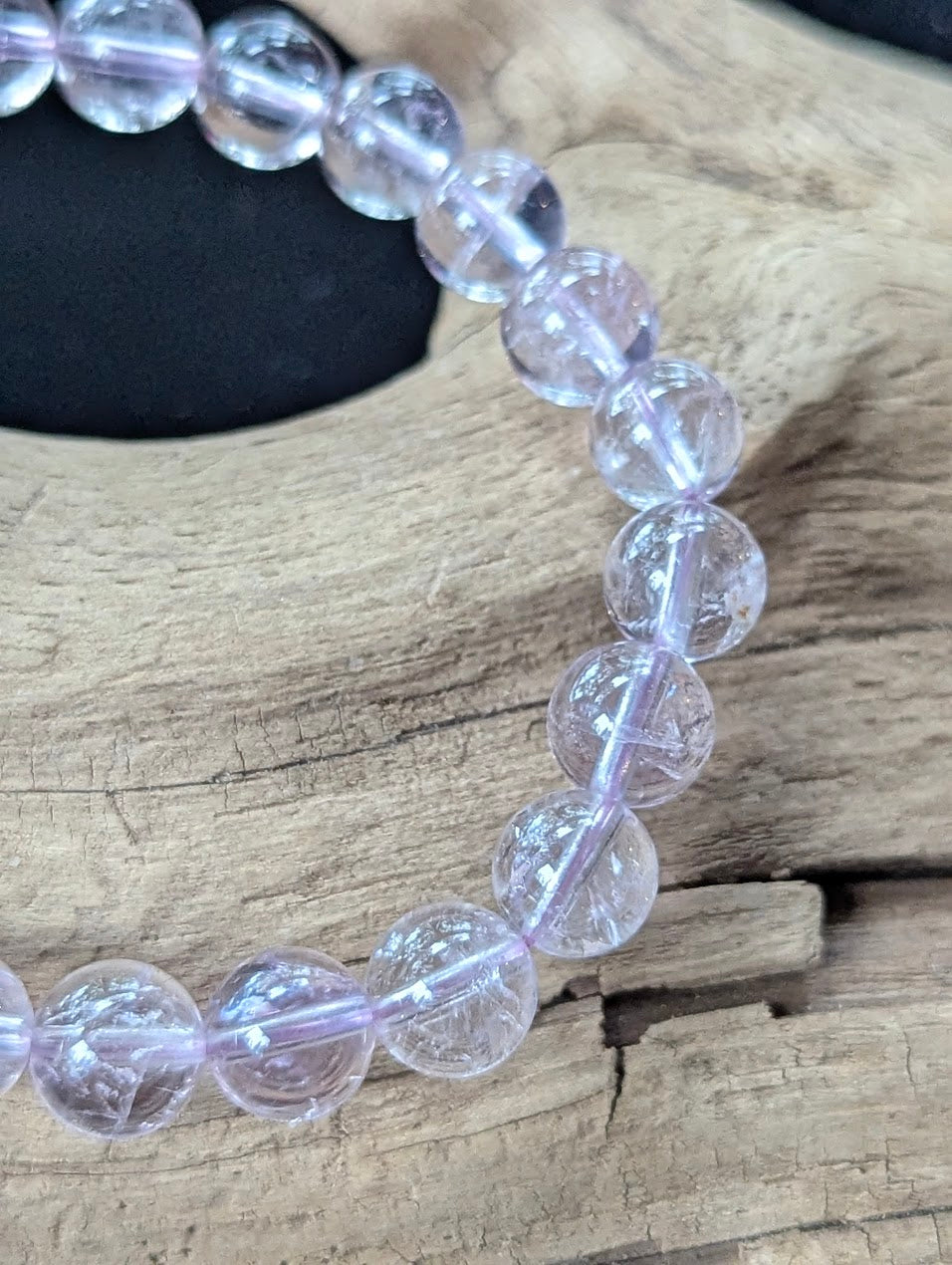 Detailed macro shot of 8mm Bolivian Light Amethyst beads displaying pristine clarity and soft purple light refraction.