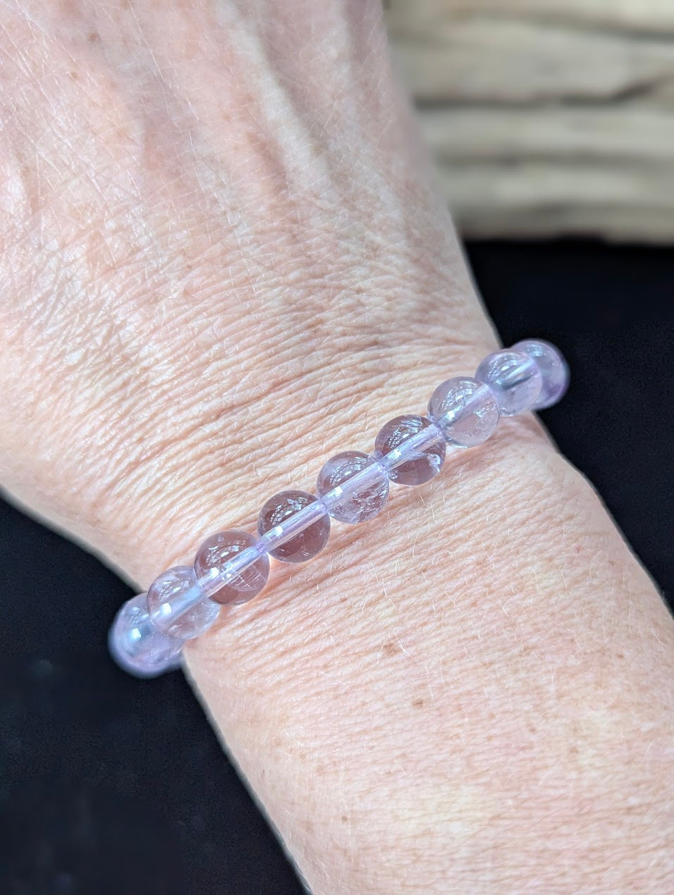 Elegant 8mm Light Amethyst gemstone bracelet styled on a wrist, showing excellent scale and soothing color.